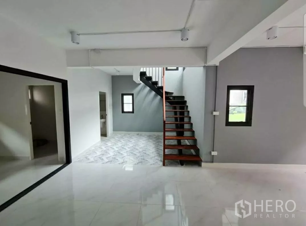 Home Office for rent in Lat Phrao, Bangkok - Staircase with dark wood treads beside a gray feature wall and marble‑look floor.