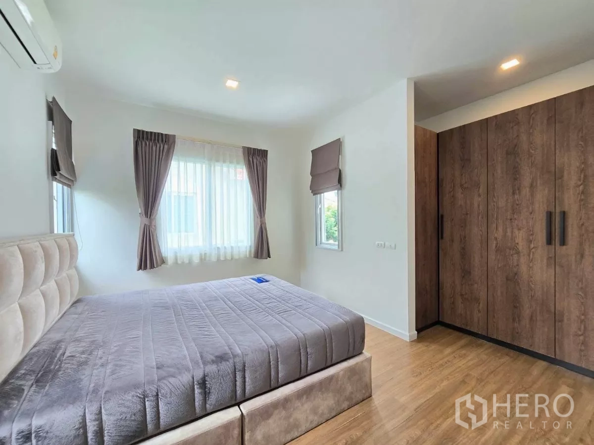 Detached House for rent in Samut Prakan - Master bedroom with large bed, fitted wardrobes, wood flooring and natural light.