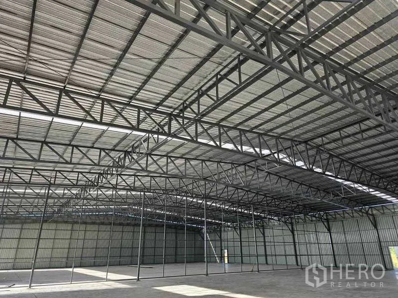 Warehouse for rent in Pak Kret, Nonthaburi - Interior view of multiple steel trusses creating large column-free bays with daylight.