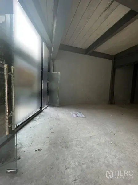 Retail Space for rent - Unfurnished retail interior with high ceiling, concrete floor and frosted glass storefront at the entrance.