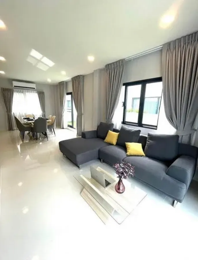 Detached House for rent - Long living–dining area with L-shaped sofa, glossy tile floors and large windows.