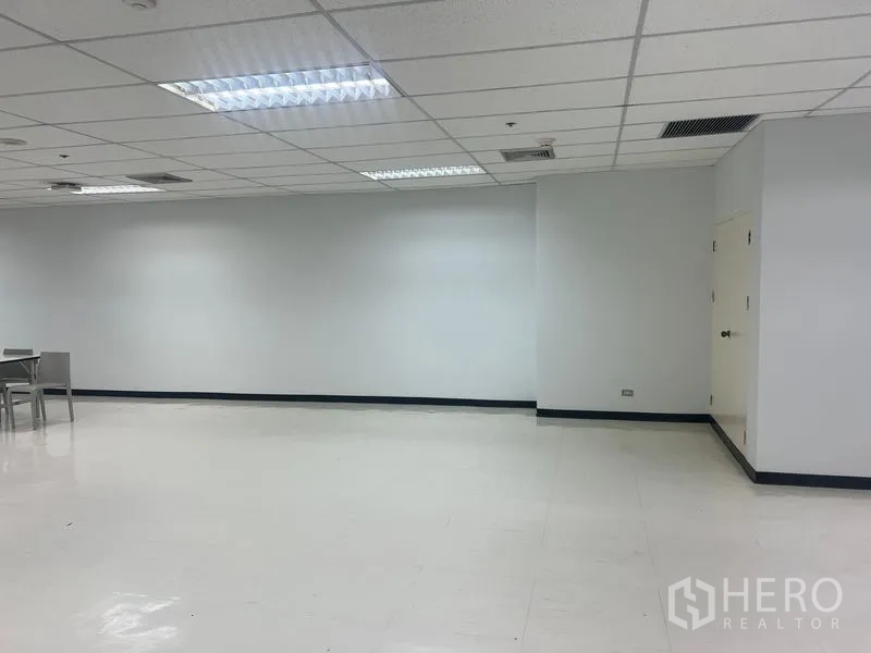 Office Space for rent in Watthana, Bangkok - Spacious empty office interior with white flooring, suspended ceiling, and storage doors.