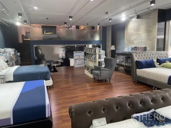 Retail Space for rent - Double-volume retail unit with mezzanine level, spotlights, shelving and lounge seating in a modern showroom layout.