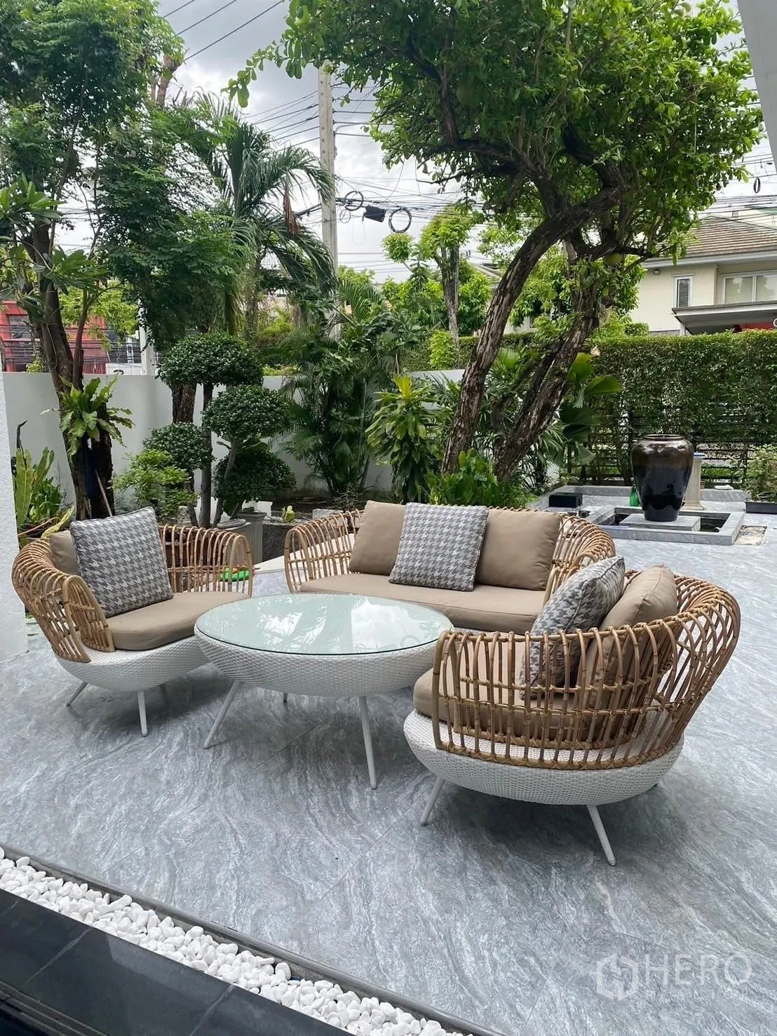 Detached House for rent in Suan Luang, Bangkok - Outdoor terrace with rattan sofas and a round glass coffee table amid greenery.