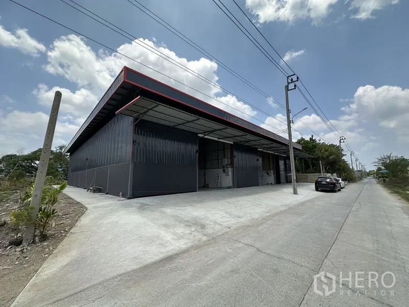 Warehouse for rent in Khlong Sam Wa, Bangkok - Angled street view showing the warehouse facade, canopy, and truck‑friendly driveway.
