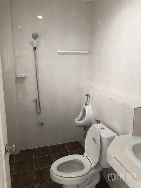 Factory for rent in Pak Kret, Nonthaburi - Bathroom with toilet, urinal, shower and sink, fully tiled.