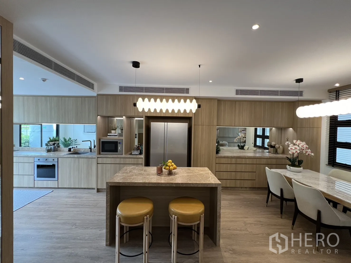 Townhouse for sale in Watthana, Bangkok - Kitchen island with lemons, sliding doors to a green patio and abundant daylight.