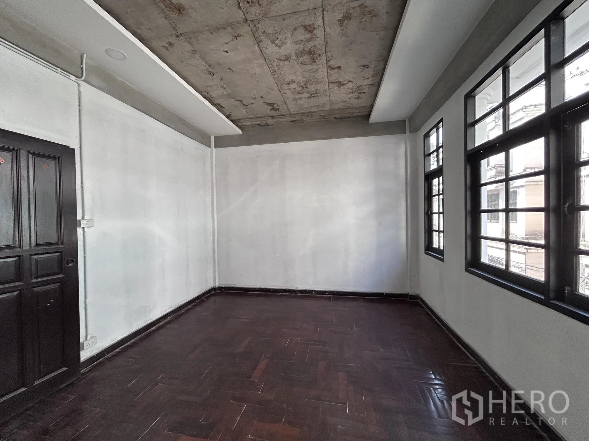 Home Office for rent or sale in Watthana, Bangkok - Room with multiple grid windows, dark wood floor and doorway.