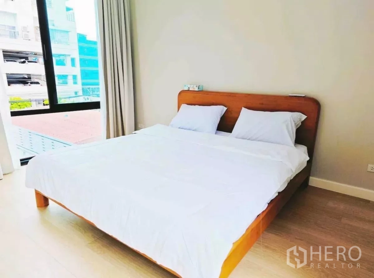 Detached House for rent in Phaya Thai, Bangkok - Minimal bedroom with wooden bedframe, white bedding and a city-view window.