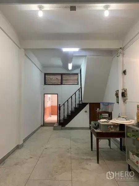 Shophouse for rent in Khlong Toei, Bangkok - Long ground-floor retail space with staircase to upper floors and bright ceiling lights.