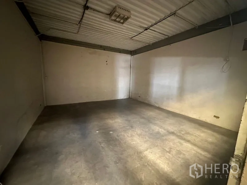 Warehouse for rent in Suan Luang, Bangkok - Empty office or storage room with concrete floor and metal ceiling panels.