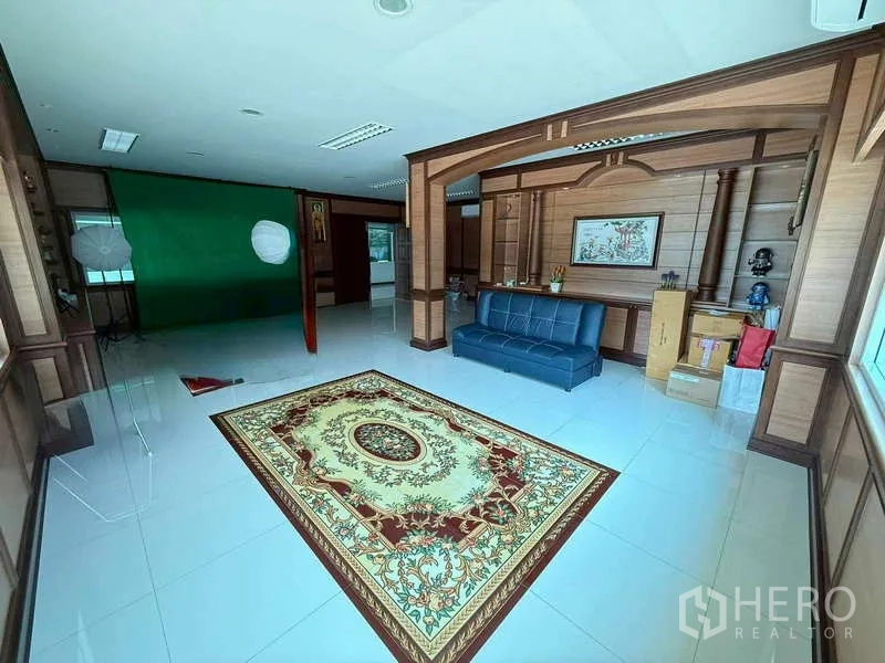 Warehouse for rent in Mueang Samut Prakan, Samut Prakan - Executive office with wood paneling, blue sofa and decorative rug on glossy tiles.