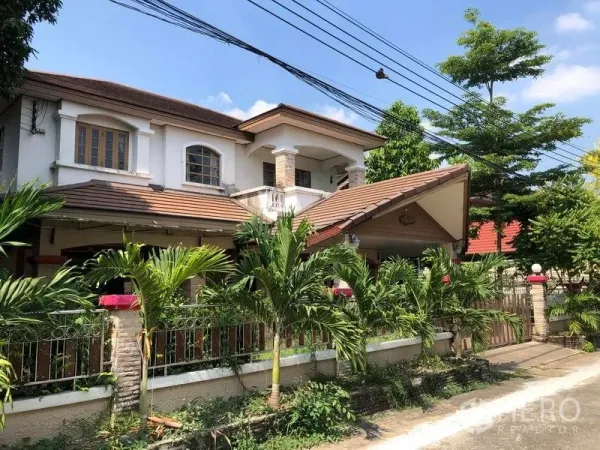 บ้าน ขายในPak Kret, Nonthaburi - มุมมองด้านข้างบ้านเดี่ยว ปากเกร็ด มีที่จอดรถมีหลังคา เสาแต่งหิน รั้วเหล็ก และสวนทรอปิคอลตามแนวกำแพง