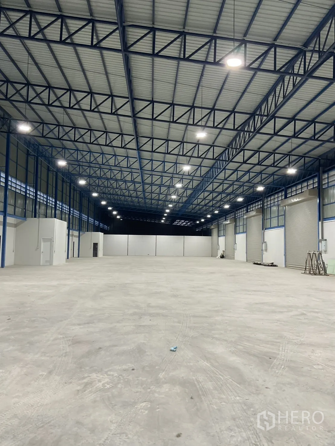 Warehouse for rent in Bang Bua Thong, Nonthaburi - Deep storage area with even concrete slab floor under blue roof trusses.