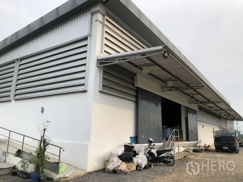Factory for rent or sale in Wang Noi, Phra Nakhon Si Ayutthaya - Factory corner showing louvered ventilation panels, canopy roofing and large roller doors.