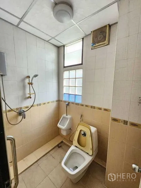 Shophouse for rent in Bang Rak, Bangkok - Bathroom with shower, toilet, urinal and high window for ventilation.