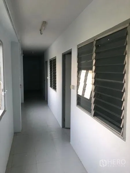 Factory for rent in Pak Kret, Nonthaburi - Corridor with louvered windows and several doors to offices or staff rooms.
