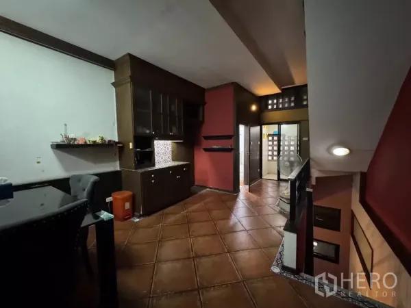 Shophouse for rent in Bang Rak, Bangkok - Warm dining and pantry area with terracotta floor tiles, dark wood cabinets, and a stairwell.