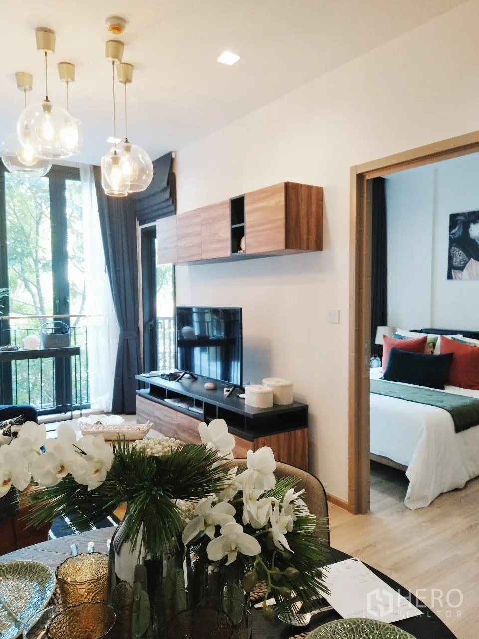 Condominium for rent in Watthana, Bangkok - Open-plan lounge with pendant lights, TV cabinet, and doorway to the bedroom.