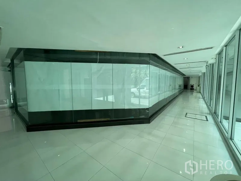 Office Space for rent in Ratchathewi, Bangkok - Bright corridor lined with floor-to-ceiling glass and a central glass showroom-style enclosure.
