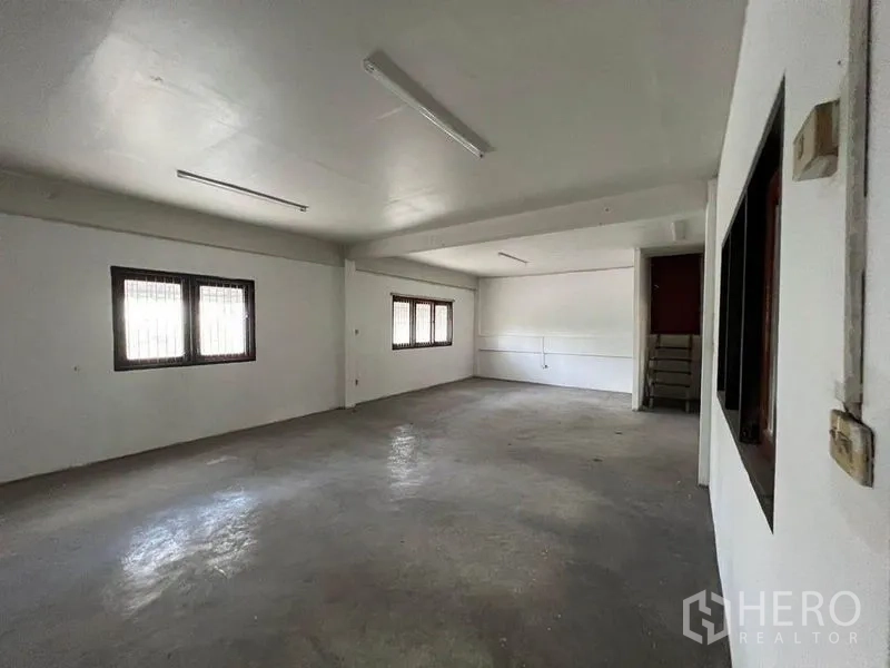 Warehouse for rent in Khlong Toei, Bangkok - Secondary workspace with barred windows and fluorescent strip lighting.
