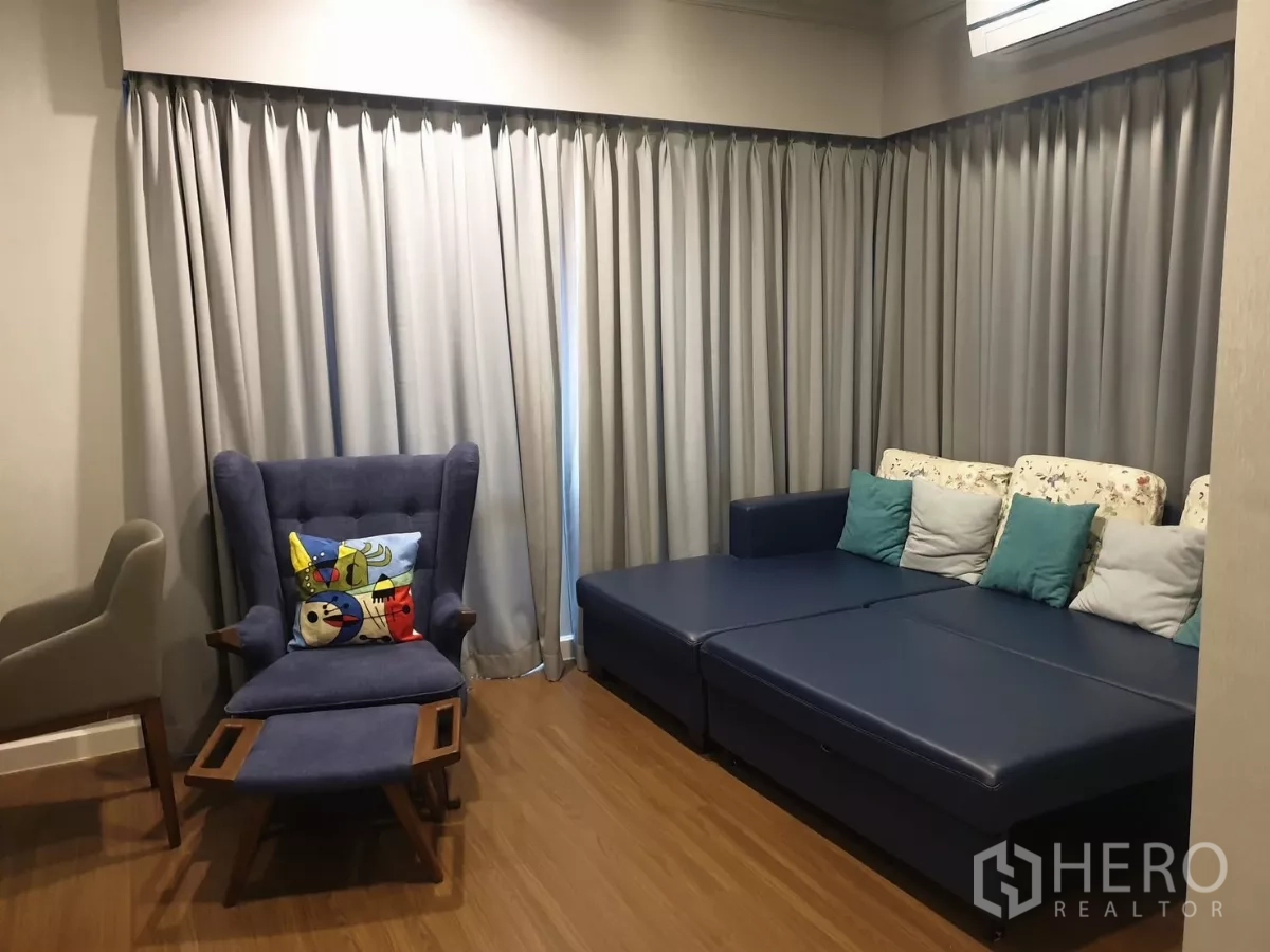 Detached House for rent or sale in Prawet, Bangkok - Second living room with blue sofa, wing chair and full-length curtains