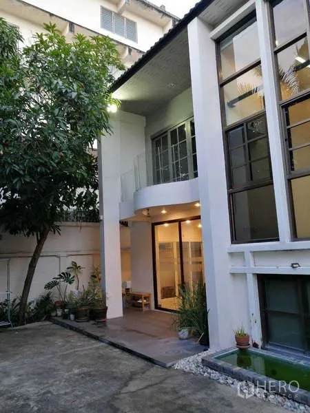 Home Office for rent in Watthana, Bangkok - Courtyard entrance and modern facade with balcony and potted plants.