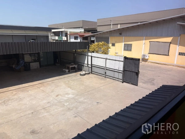 Warehouse for rent in Lat Krabang, Bangkok - Upper-level view into the concrete loading yard and sliding gates of the warehouse complex.