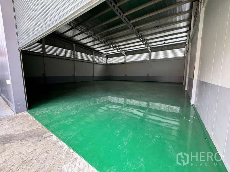 Factory for rent or sale in Lam Luk Ka, Pathum Thani - Warehouse opening with roller shutter showing a large clear floor and ventilated walls.