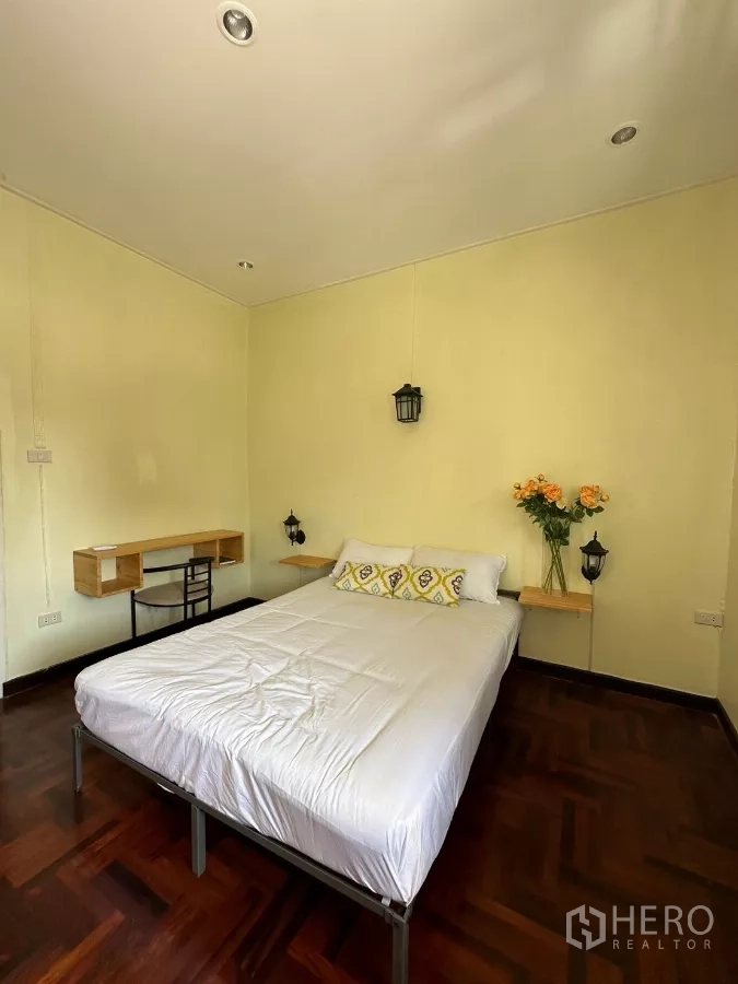 Home Office for rent in Suan Luang, Bangkok - Bedroom with bed, small desk nook, and wooden floors.