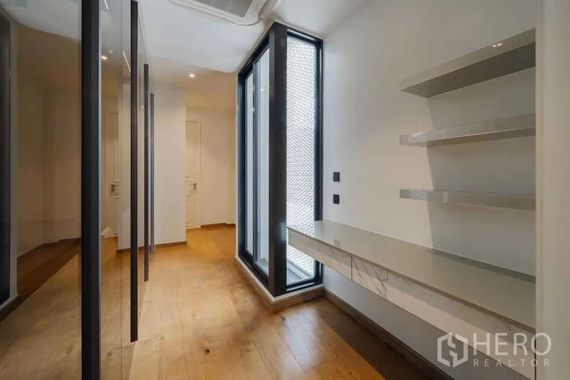 Townhouse for rent or sale in Watthana, Bangkok - Walk-in closet with desk, shelving, and floor-to-ceiling windows with patterned screens.
