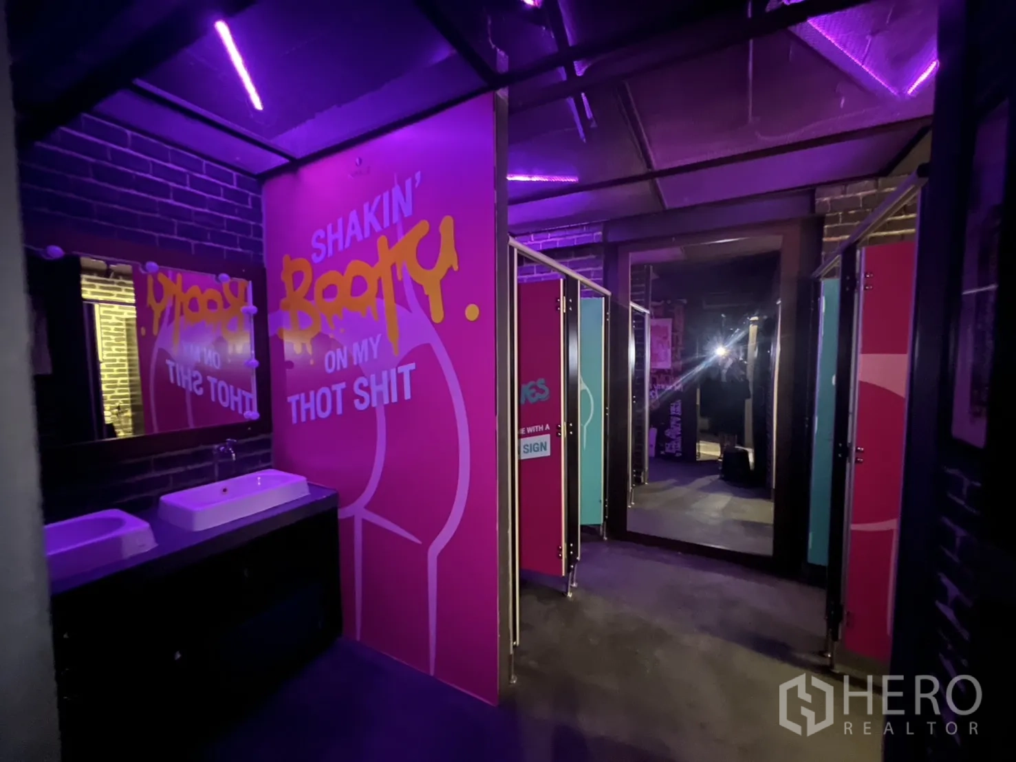 Retail Space for rent in Bangkok - Women’s restroom with bold pink graphics, stalls and vanity sinks.