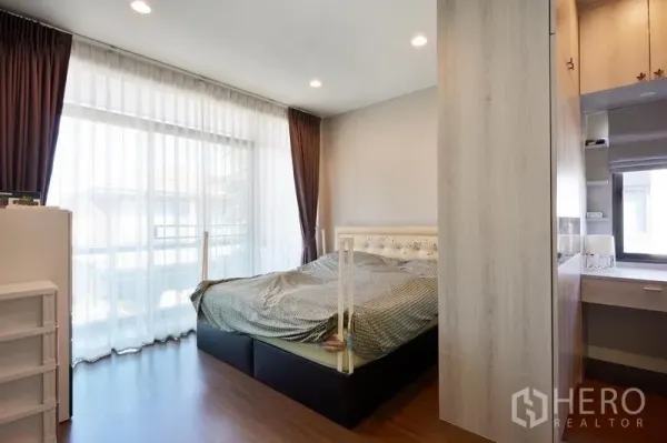 Detached House for rent or sale in Bang Kapi, Bangkok - Bright master bedroom with floor-to-ceiling windows, sheer curtains, wood flooring and built-in wardrobe with dressing nook.
