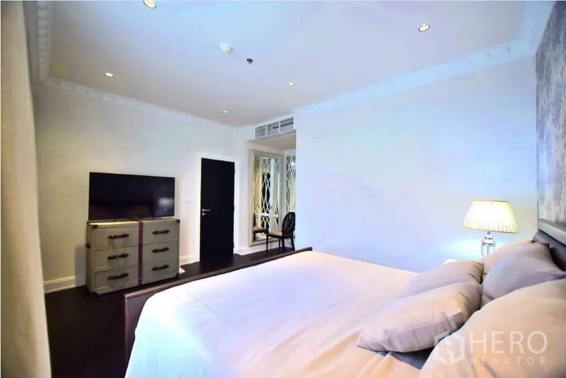 Condominium for rent or sale in Khlong Toei, Bangkok - Bedroom with TV console, dresser and soft ambient lighting.