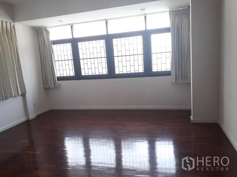 Detached House for rent in Watthana, Bangkok - Large bedroom with a wall of windows, curtains and glossy wooden floors