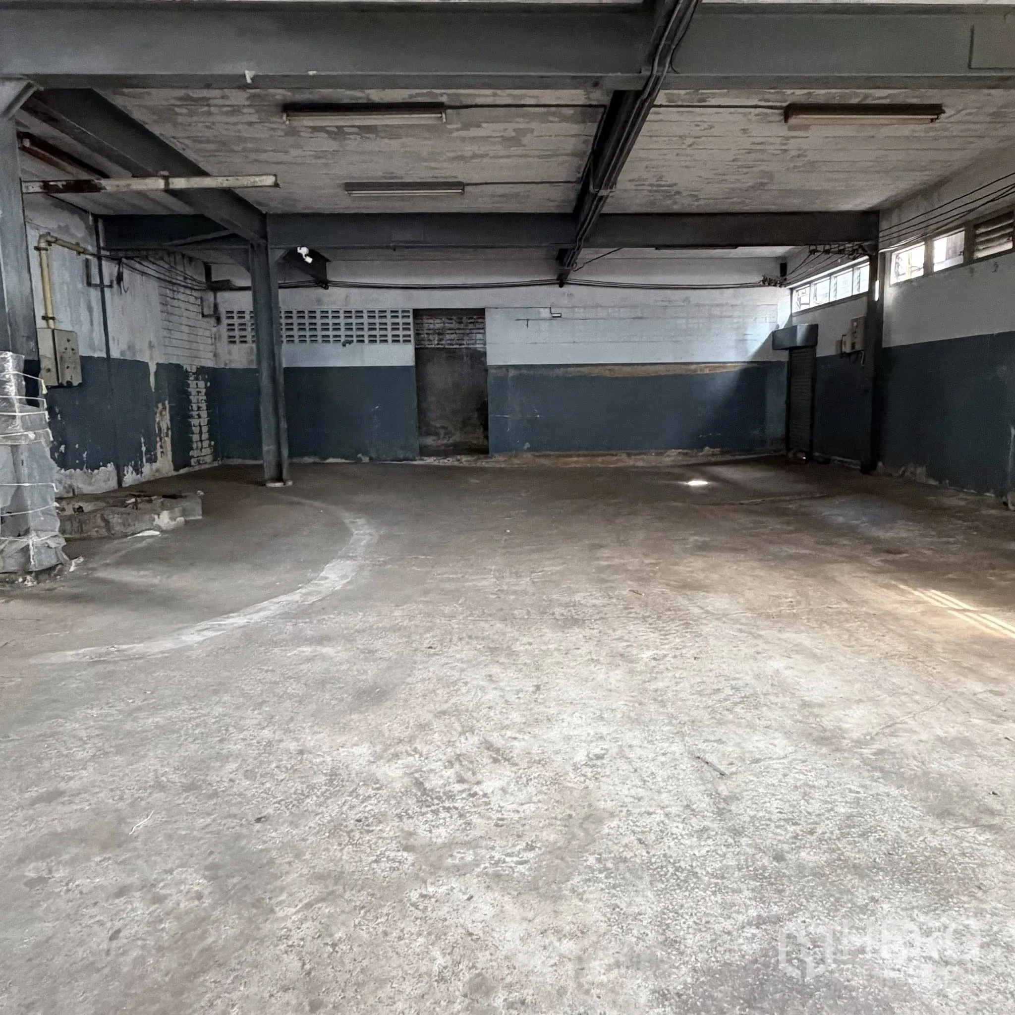 Factory for rent in Phra Pradaeng, Samut Prakan - Empty warehouse area with concrete floor, steel columns, and a high ceiling.