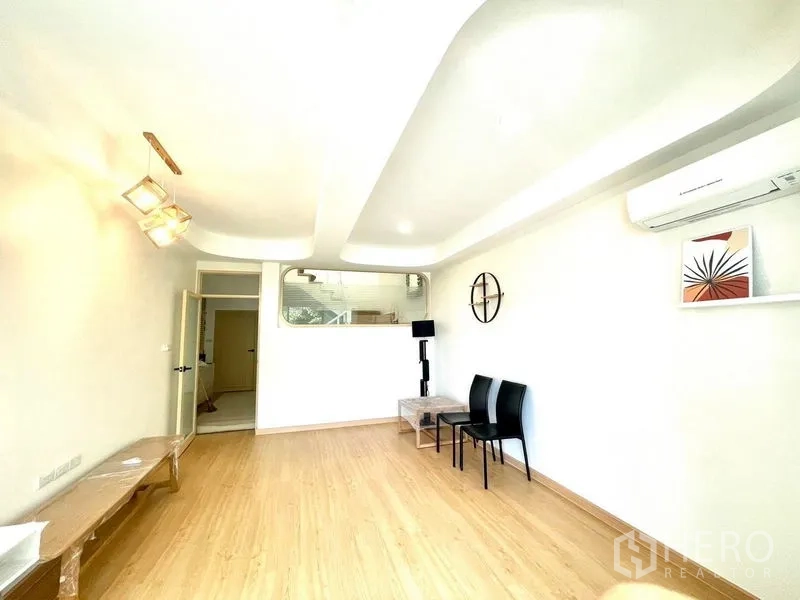 Townhouse for rent in Khlong Toei, Bangkok - Flexible living room with wood floors, recessed ceiling and interior window.