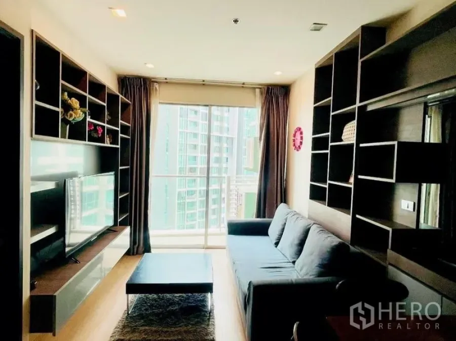 Condominium for rent - Living room toward the balcony with TV console and floor-to-ceiling glass.