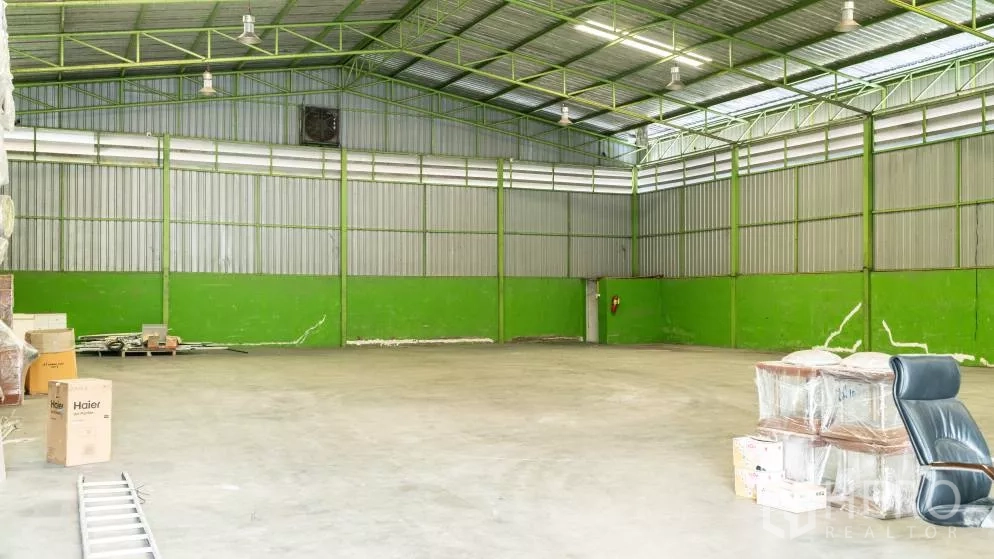 Warehouse for rent in Thanyaburi, Pathum Thani - Empty warehouse section with smooth concrete floor, steel frame ceiling and a wall-mounted ventilation fan.