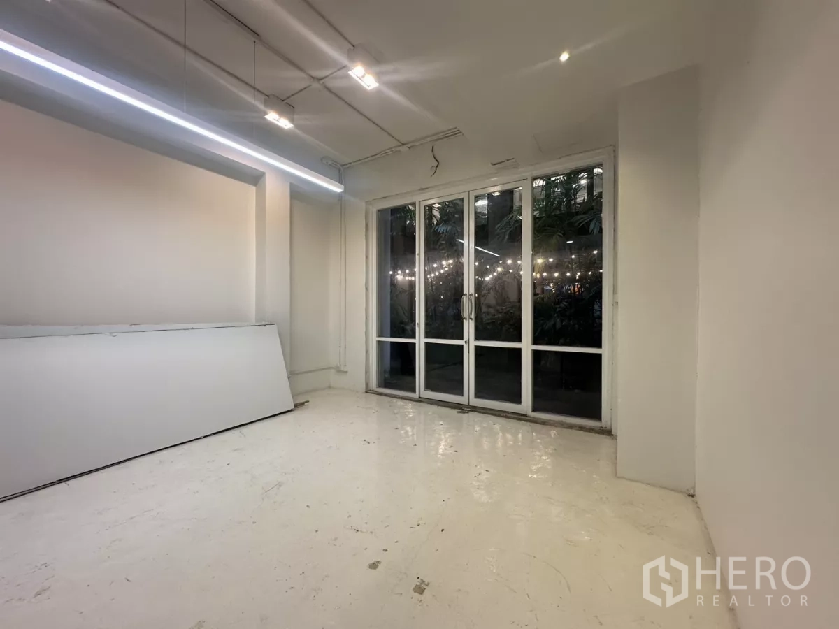 Home Office for rent in Pathum Wan, Bangkok - Bright workspace with long LED strip lighting and full-height glass doors facing greenery.