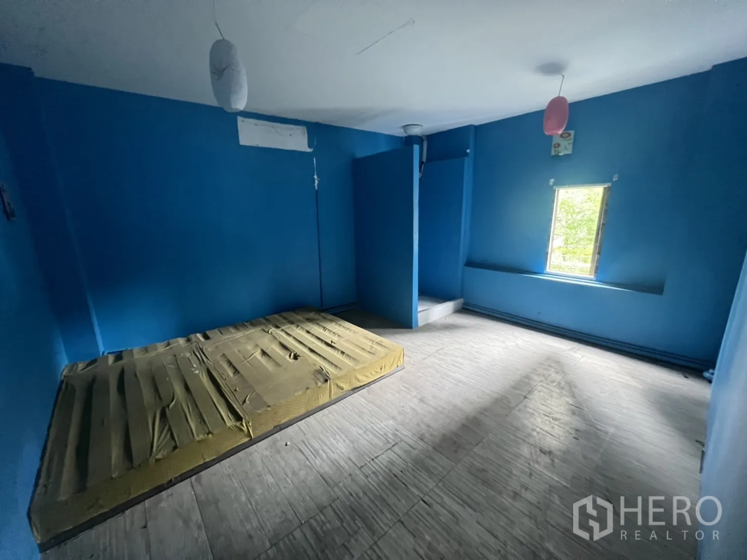 Shophouse for rent in Watthana, Bangkok - Upper-floor room with blue walls, a window and a built-in raised platform.