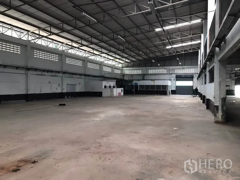 Factory for rent in Mueang Chon Buri, Chon Buri - Warehouse interior with roller shutter loading door, bright roof lights and open concrete floor.