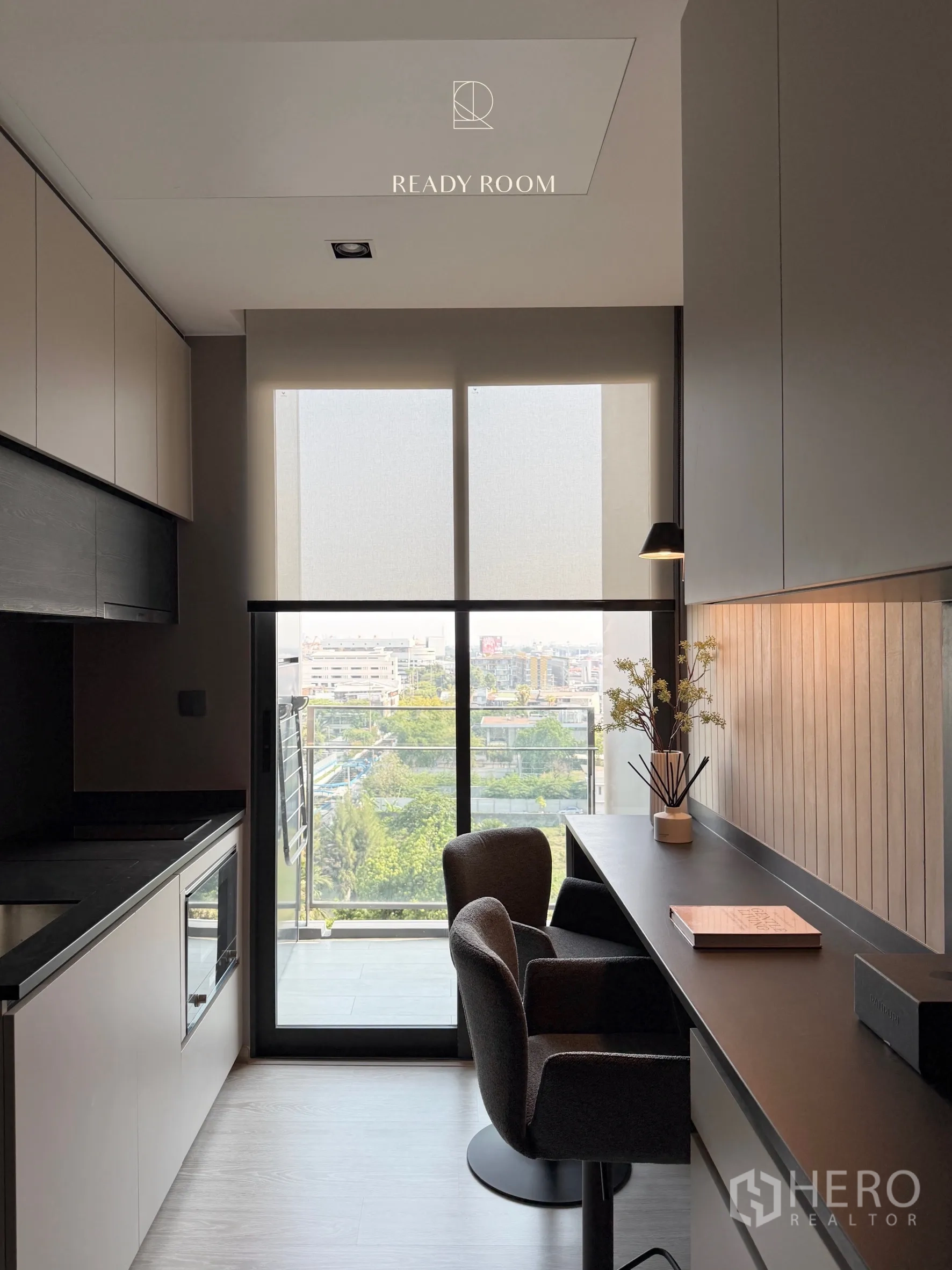Condominium for rent in Khlong Toei, Bangkok - Compact kitchen and study area opening to a balcony with a city view.