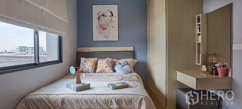 Townhouse for rent in Prawet, Bangkok - Bright bedroom with blue accent wall, bed by the window, wardrobe and vanity.
