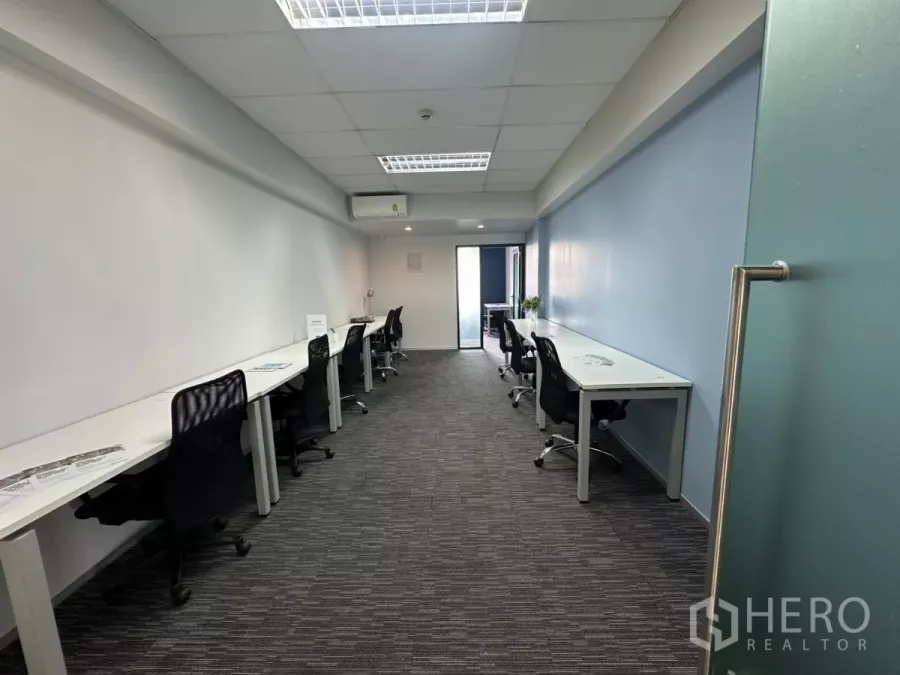 Office Space for rent in Watthana, Bangkok - Long furnished office with white desks, black chairs, carpet tiles and a glass door in Thonglor.