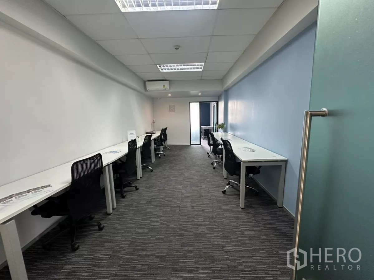 Office Space for rent in Watthana, Bangkok - Long furnished office with white desks, black chairs, carpet tiles and a glass door in Thonglor.