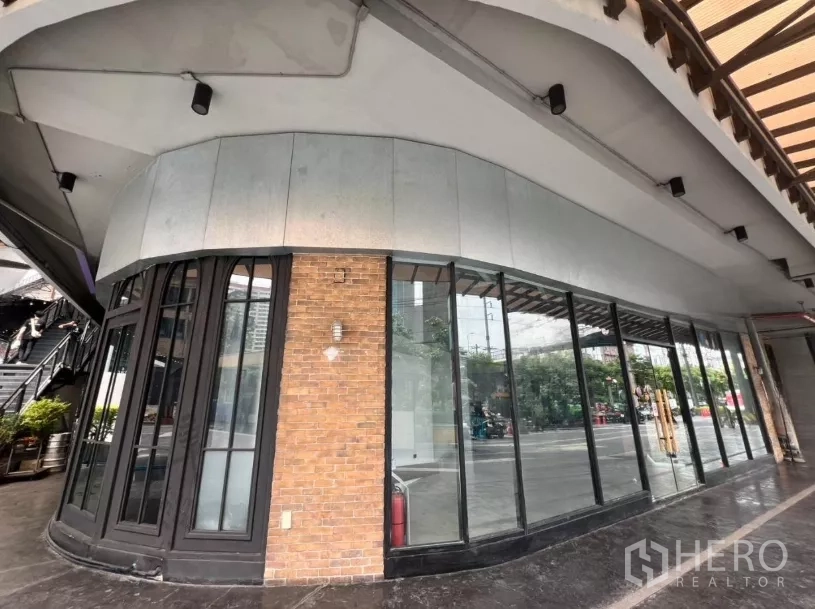Retail Space for rent - Curved corner facade with a brick pillar and wraparound floor-to-ceiling windows offering standout signage opportunities.