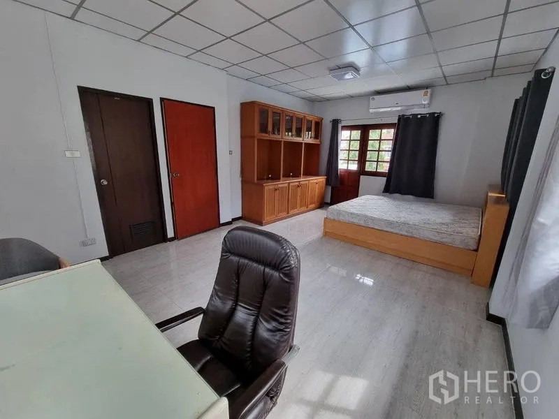 Detached House for rent in Nonthaburi - Large bedroom with built-in wooden shelves, desk, and a double bed.