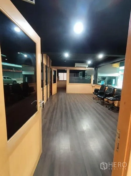 Warehouse for rent in Bang Phli, Samut Prakan - Interior corridor with wood-framed glass offices and a dark ceiling.