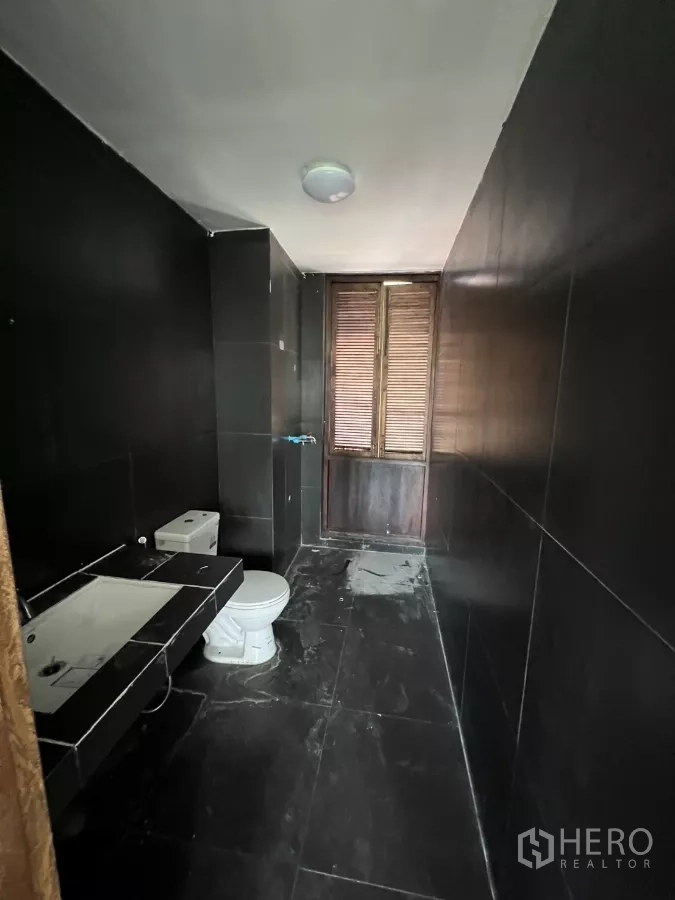 Retail Space for rent in Khlong Toei, Bangkok - Long black-tiled washroom with toilet and sink.